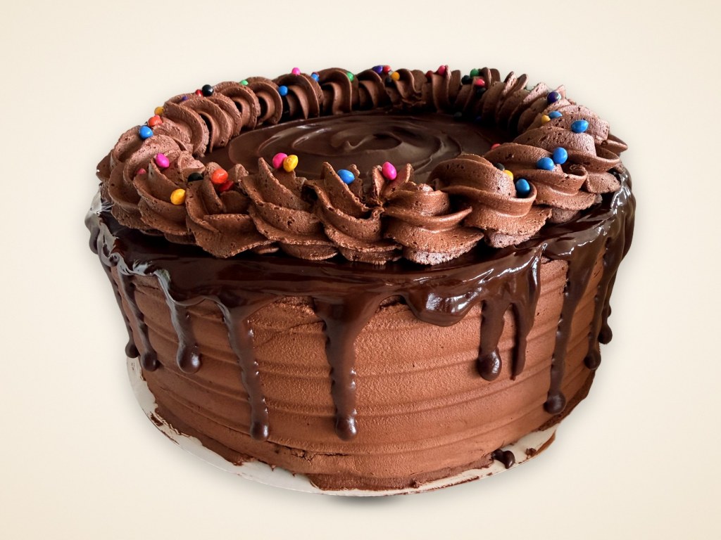 Chocolate buttercream cake with a glossy chocolate drip, piped rosettes and candy-coated chocolates
