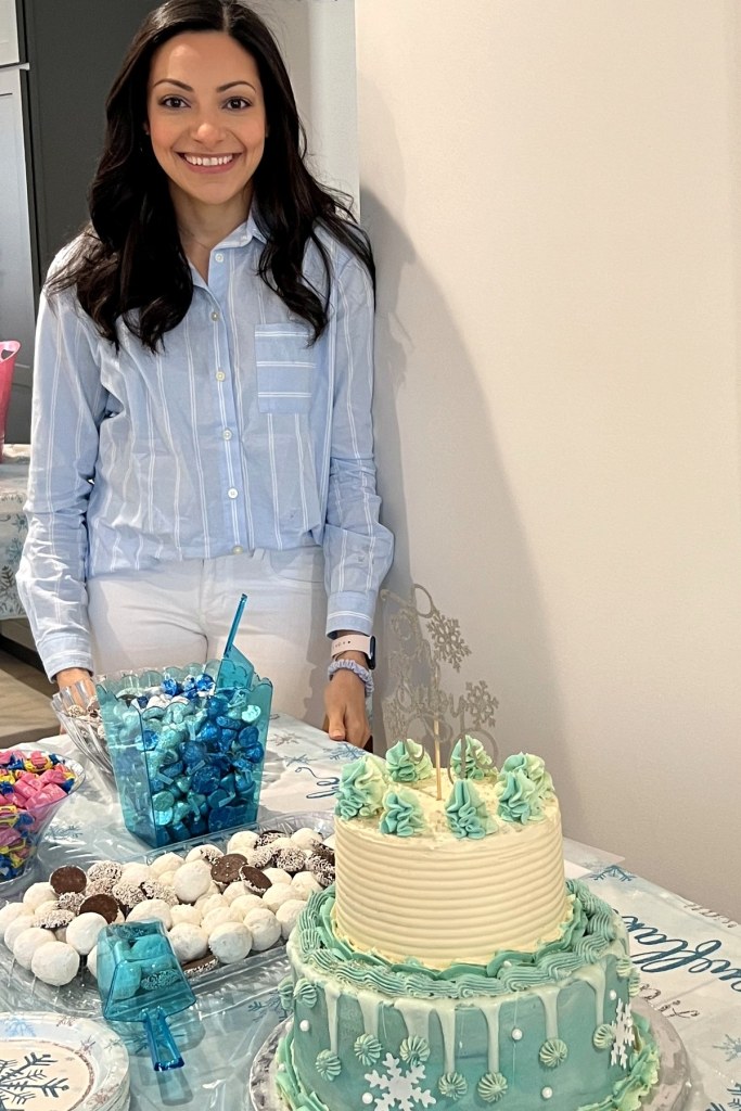 Dr. Bisant Labib smiling beside a two-tier blue and white snowflake cake she made