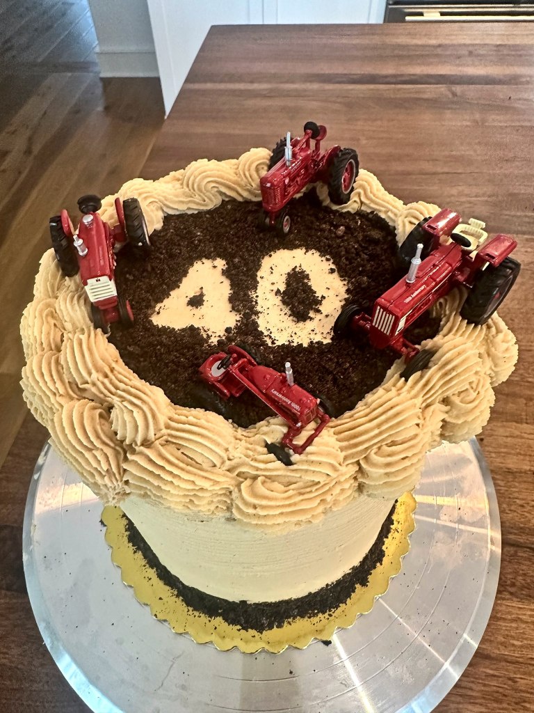 Birthday cake with a cookie crumb dirt top, the number 40 and red toy tractors
