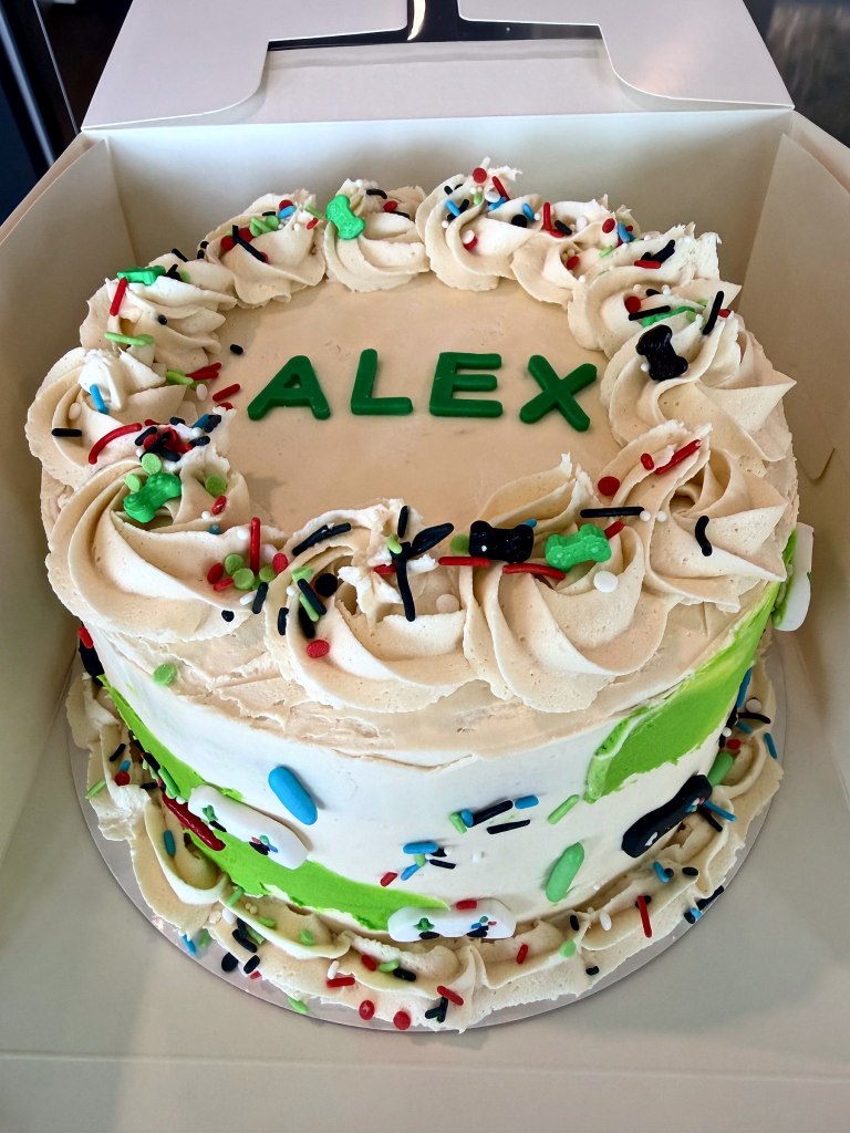 White and green birthday cake with sprinkles and a name in green letters