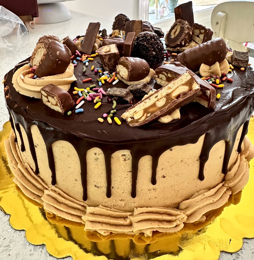 Drip cake piled high with candy bars, chocolates and rainbow sprinkles