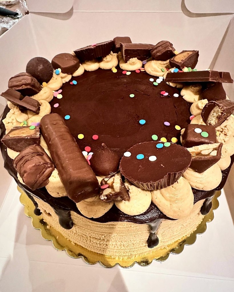 Chocolate cake topped with candy bars, peanut butter cups and colorful candies