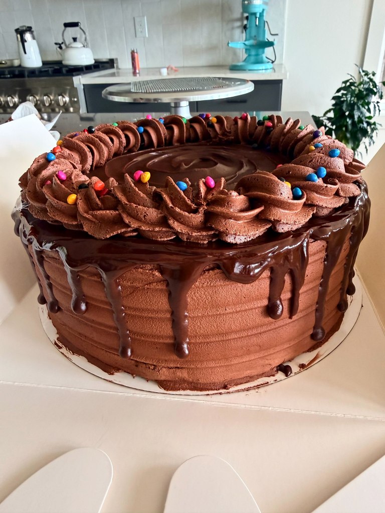 Chocolate cake with a chocolate drip, chocolate rosettes and colorful candies