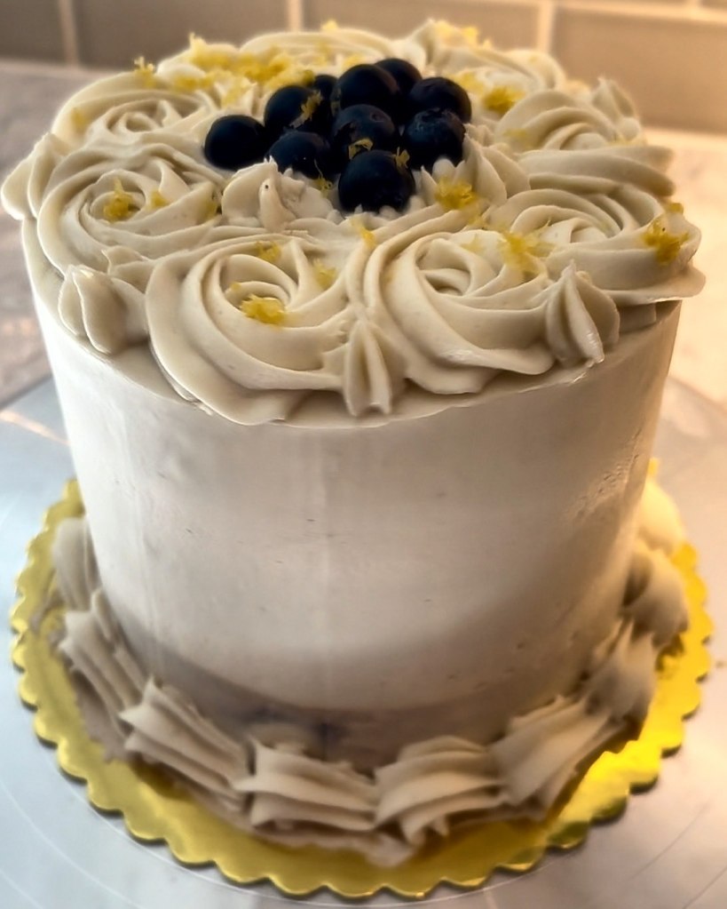 White cake with frosting rosettes, fresh blueberries and lemon zest
