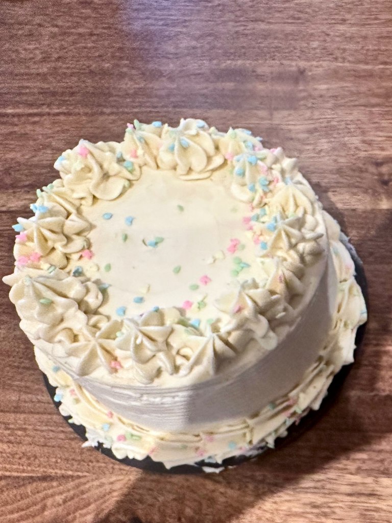 White cake with frosting swirls and pastel sprinkles