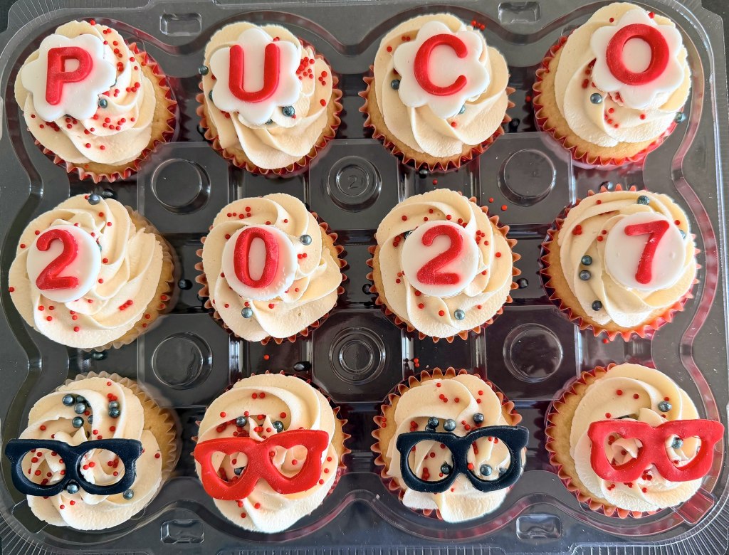Cupcakes spelling PUCO 2027, with red and black eyeglasses decorations