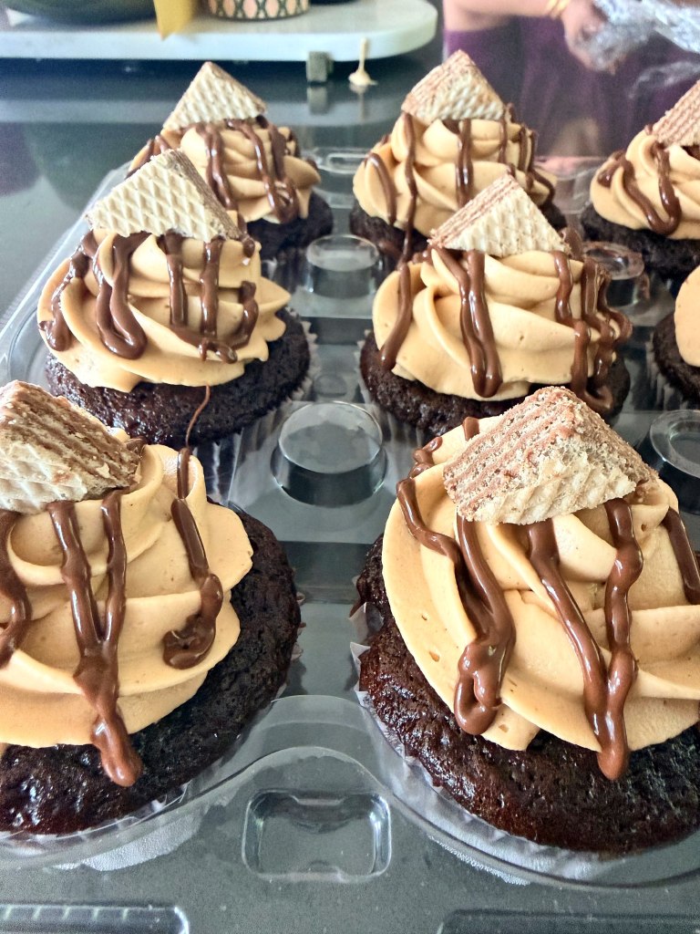 Chocolate cupcakes with tall frosting swirls, a chocolate drizzle and wafer cookie triangles
