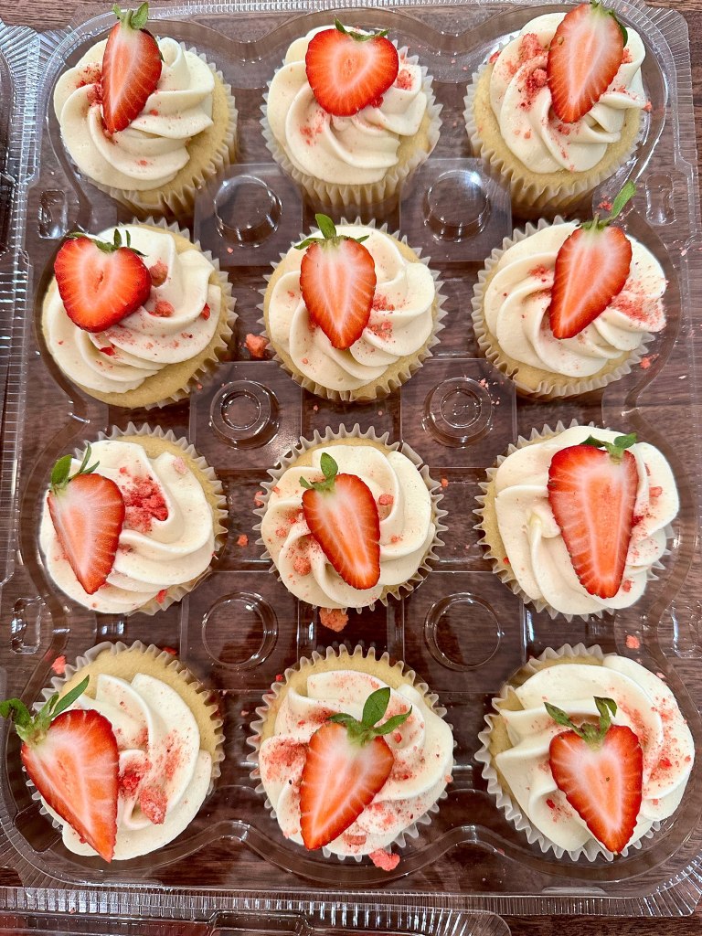 Cupcakes with cream frosting, fresh strawberries and pink sprinkles