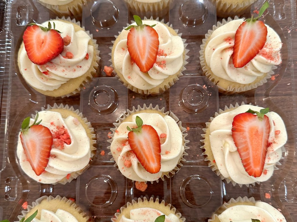 Vanilla cupcakes with buttercream swirls and fresh strawberry halves